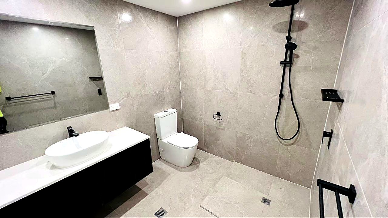 Contemporary bathroom renovation with large-format tiles and black fixtures